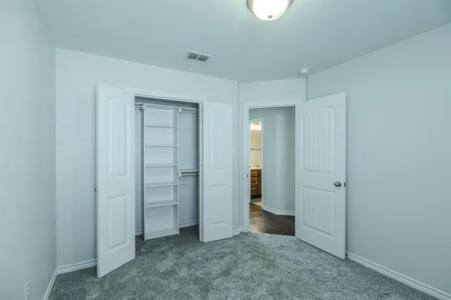 an empty room with closet and mirror