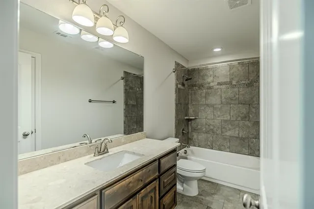 a bathroom with a granite countertop sink a toilet and shower