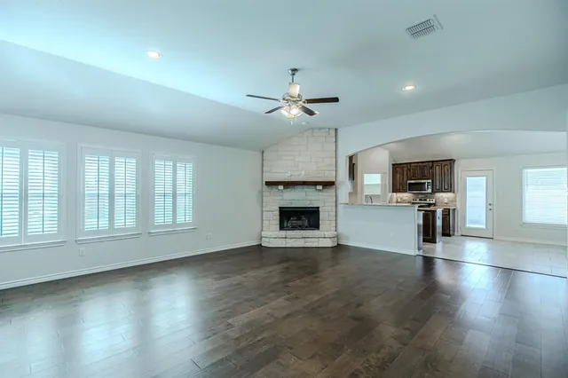 an empty room with wooden floor fireplace and windows
