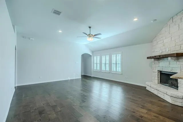 an empty room with wooden floor fireplace and windows
