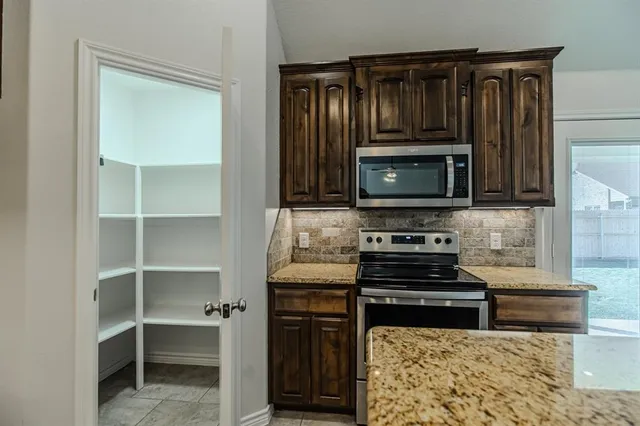 a kitchen with granite countertop a stove and a microwave