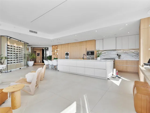 a living room with couches and kitchen view with wooden floor