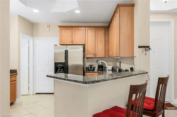 a kitchen with stainless steel appliances granite countertop a refrigerator a stove and white cabinets with wooden floors