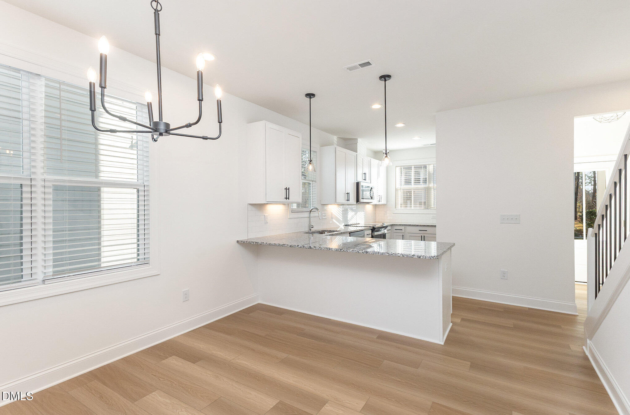 4801 Gossamer Lane, Unit 106 Raleigh, NC 27616 - Photo 9 of 42 a kitchen with kitchen island a wooden floor and a chandelier