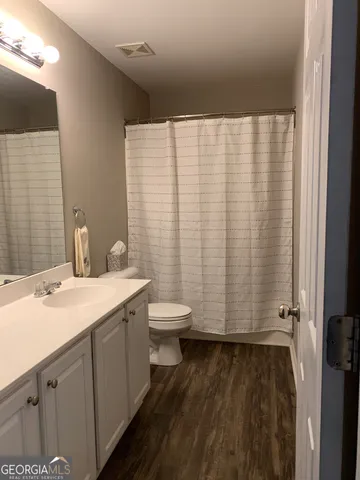a bathroom with a granite countertop sink toilet and a mirror