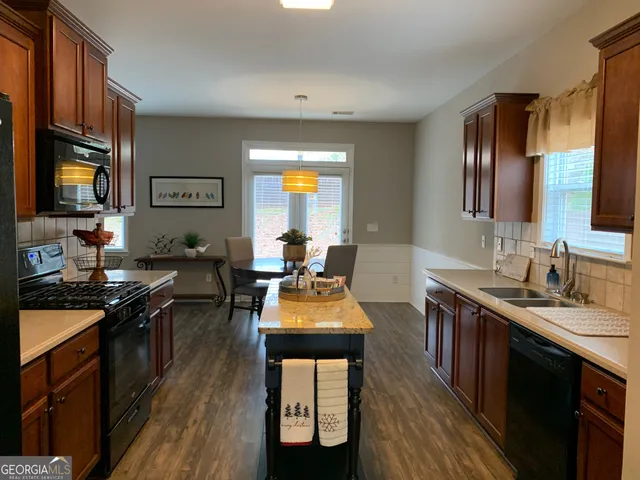 a kitchen with stainless steel appliances granite countertop wooden cabinets a stove top oven a sink and dishwasher