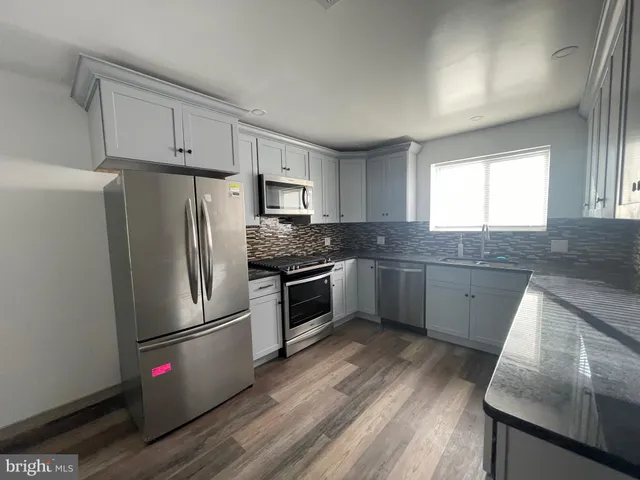 a kitchen with granite countertop appliances a sink cabinets and a window