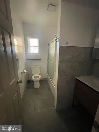 a bathroom with a granite countertop sink toilet and a mirror