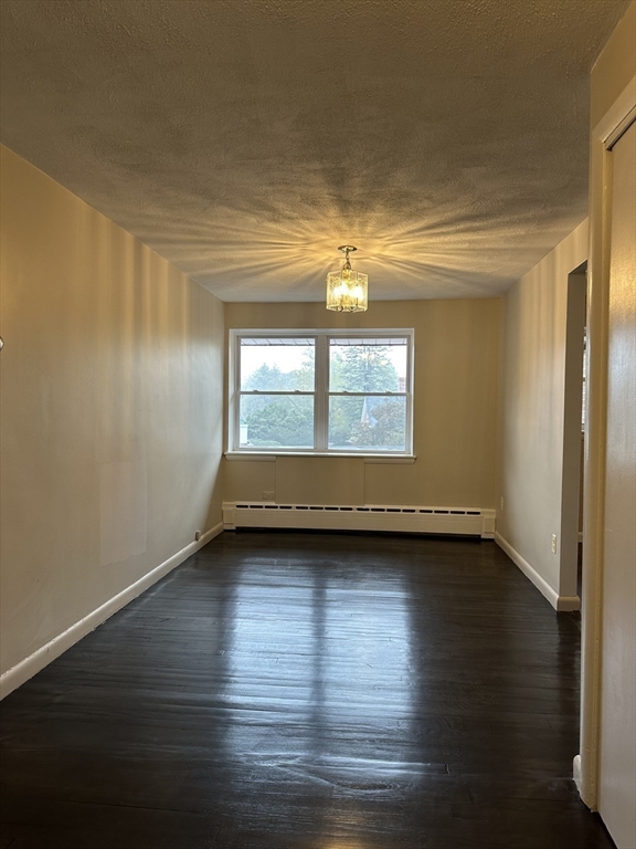 79 Wyman Street, Unit D Newton, MA 02468 - Photo 3 of 12 an empty room with wooden floor and windows