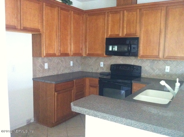 12988 Spring Rain Road Jacksonville, FL 32258 - Photo 3 of 10 a kitchen with stainless steel appliances granite countertop a sink a stove and a microwave