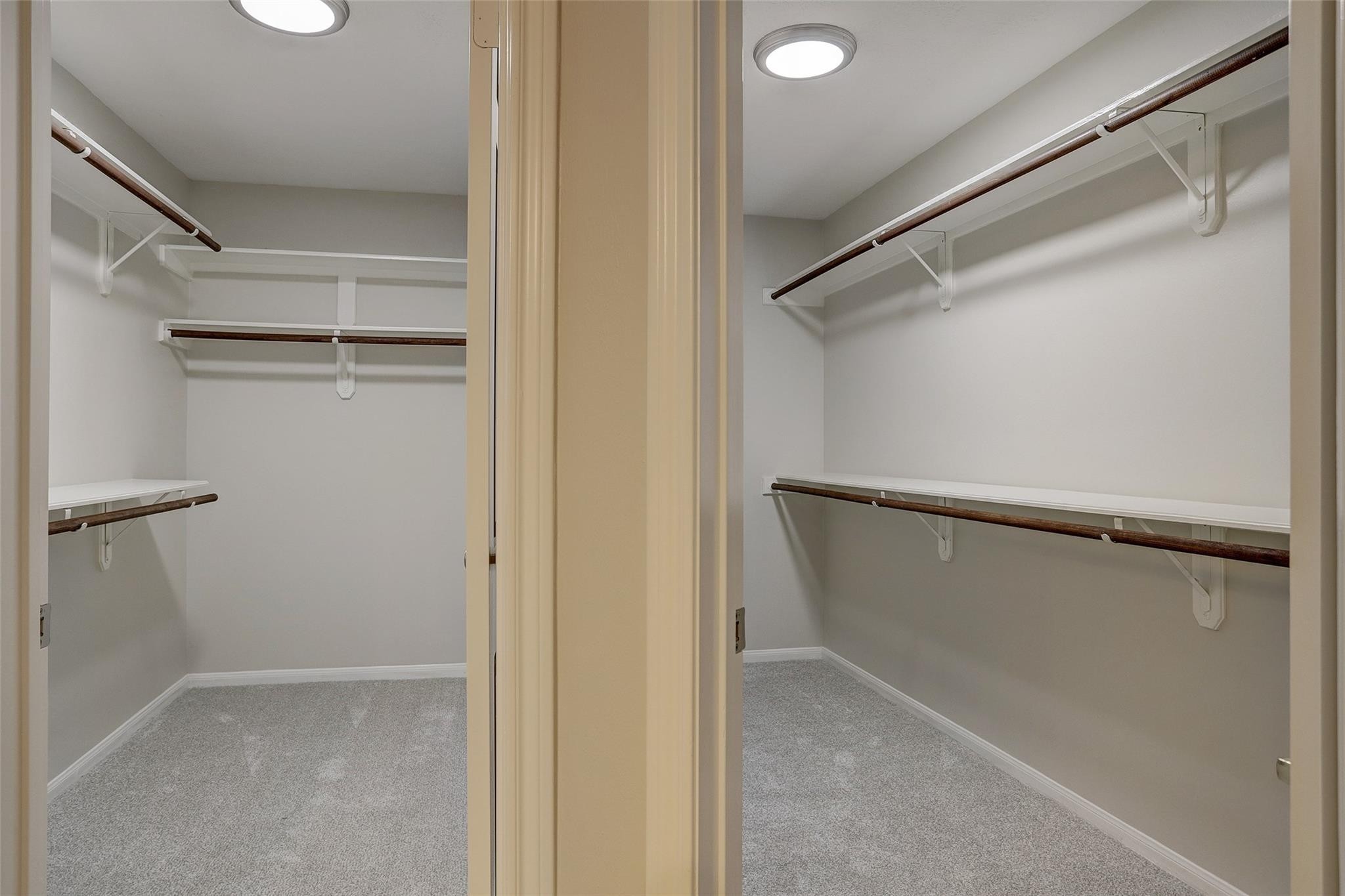 10 Heathstone Place The Woodlands, TX 77381 - Photo 14 of 27 Ultimate organization with two spacious walk-in closets, featuring ample shelving and hanging space, all wrapped in soft neutral tones and plush carpeted flooring.