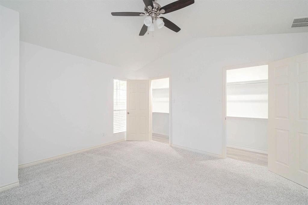 20 Abbey Road Euless, TX 76039 - Photo 6 of 8 Unfurnished bedroom featuring lofted ceiling, light carpet, ceiling fan, a spacious closet, and two closets