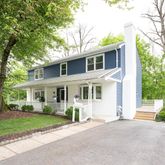 a front view of a house with a garden and trees
