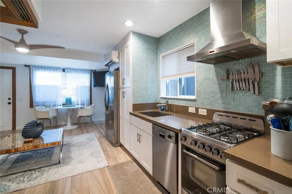 a kitchen with stainless steel appliances granite countertop a stove a sink dishwasher and cabinets with wooden floor