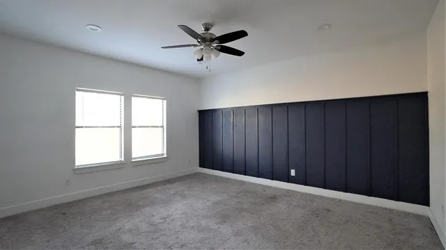 an empty room with windows and ceiling fan view