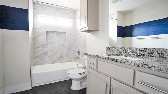 a bathroom with a granite countertop sink a toilet and bathtub