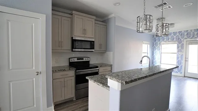 a kitchen with kitchen island granite countertop stainless steel appliances a sink stove and refrigerator