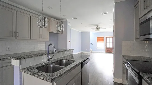 a kitchen with granite countertop a sink stainless steel appliances and cabinets