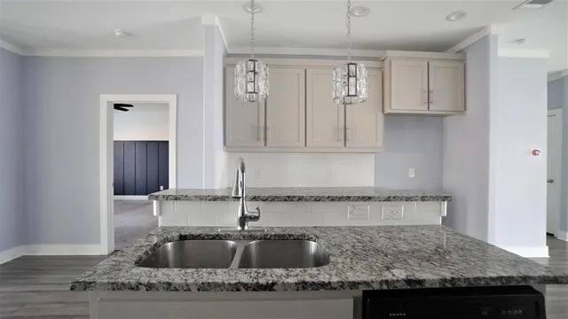 a kitchen with granite countertop a sink a stove and cabinets