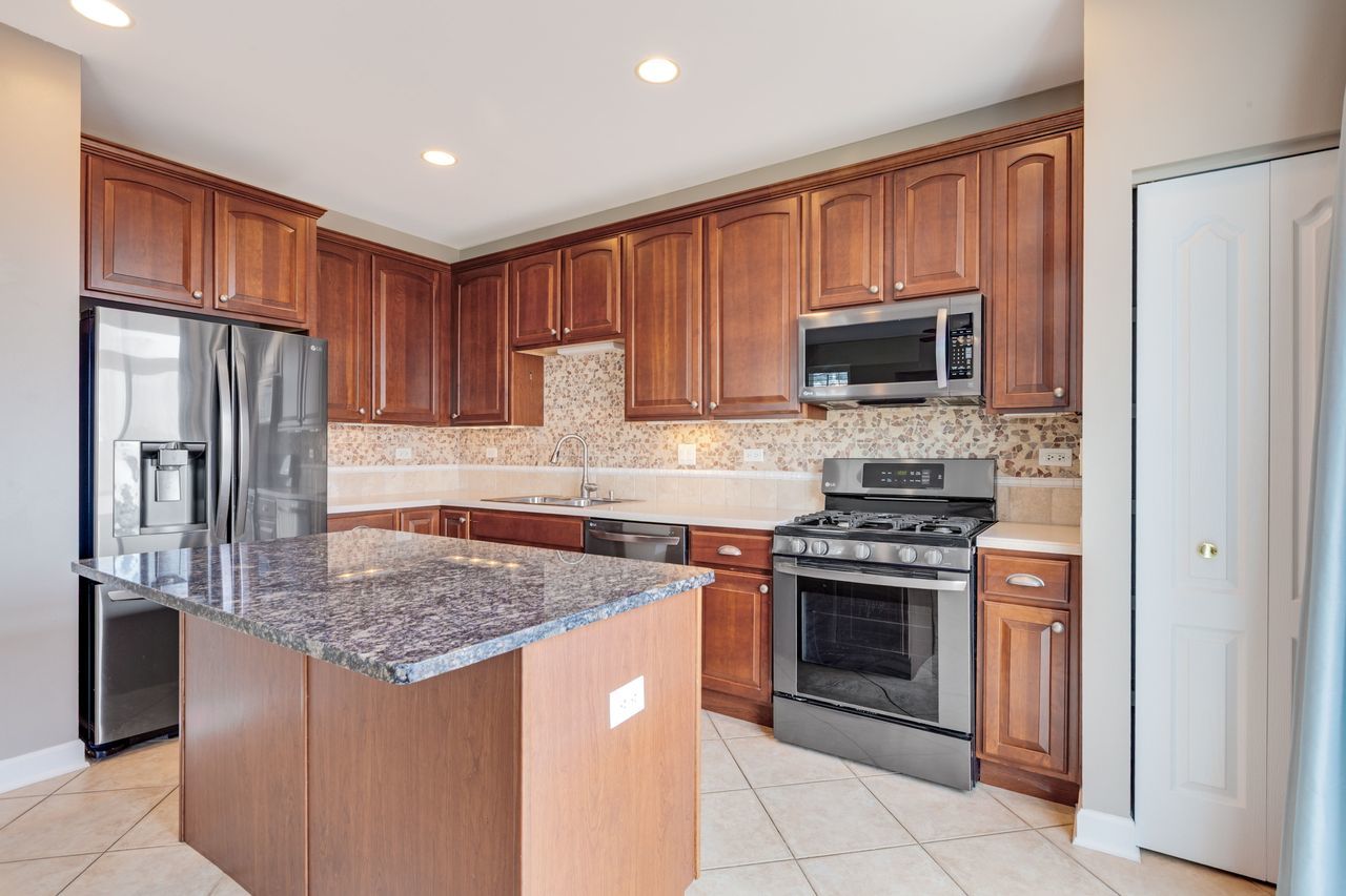 2805 Cattail Court, Unit D Wauconda, IL 60084 - Photo 6 of 30 a kitchen with stainless steel appliances granite countertop a stove refrigerator and microwave