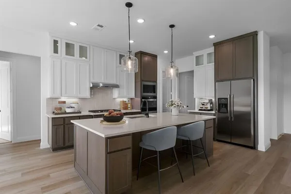 a kitchen with stainless steel appliances granite countertop a stove a refrigerator a sink a stove and a refrigerator with wooden floor