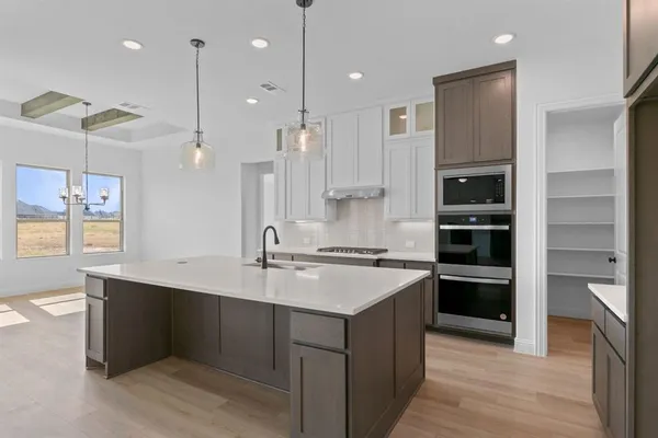 a large kitchen with a center island wooden floor stainless steel appliances and a window