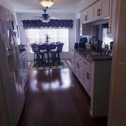 a kitchen with stainless steel appliances granite countertop a stove a sink dishwasher a dining table and chairs with wooden floor