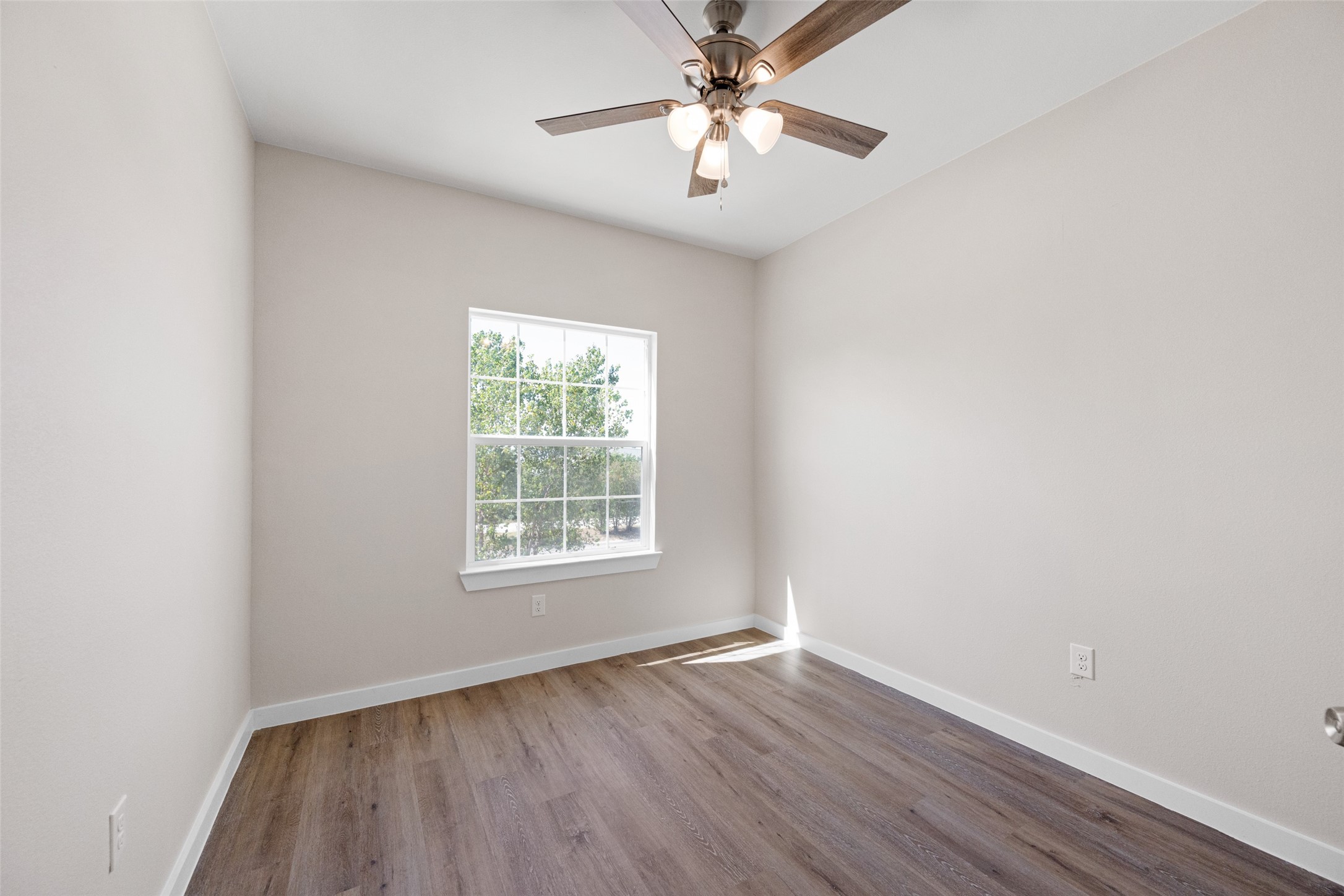 9409 Clinton Drive, Unit A Houston, TX 77029 - Photo 21 of 28 an empty room with wooden floor chandelier fan and windows