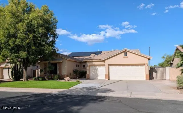 a view of a white house with a large tree and wooden fence