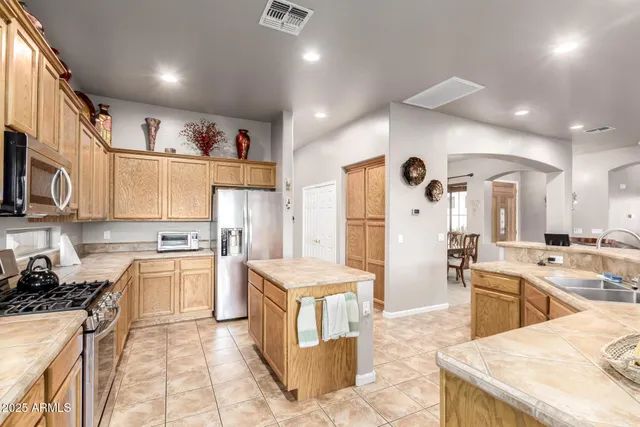 a kitchen with stainless steel appliances granite countertop a stove top oven a sink a dining table and chairs