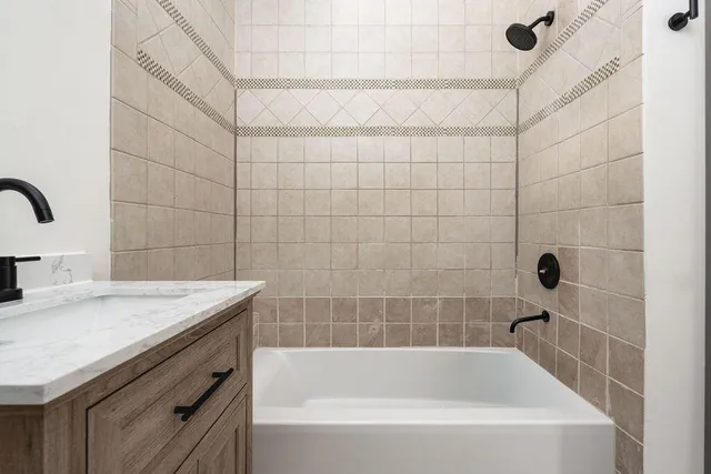 a bathroom with a granite countertop sink a bathtub and shower