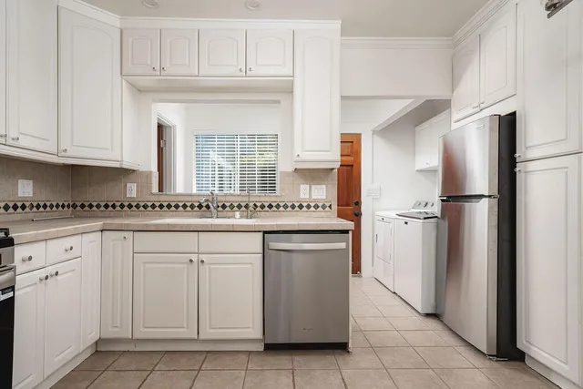 a kitchen with granite countertop white cabinets and refrigerator