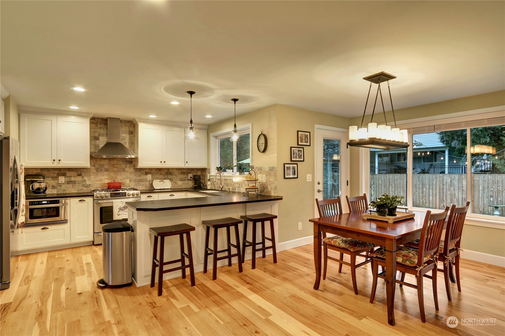120 219th Place Southwest Bothell, WA 98021 - Photo 4 of 20 a kitchen with stainless steel appliances granite countertop a stove a refrigerator a kitchen island a dining table and chairs with wooden floor