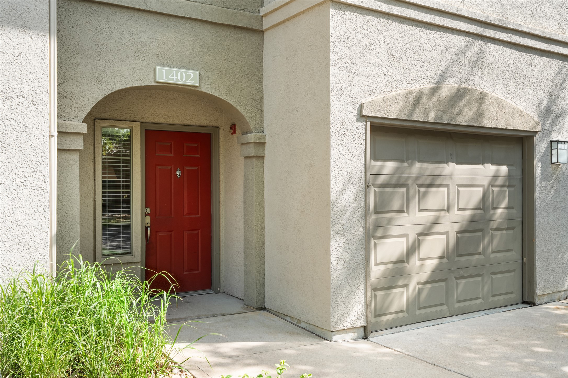 11203 Ranch Road 2222, Unit 1402 Austin, TX 78732 - Photo 2 of 22 An inviting entrance with a vibrant red door, framed by architectural stucco, leads to a private garage.