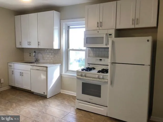 a kitchen with white cabinets and white appliances