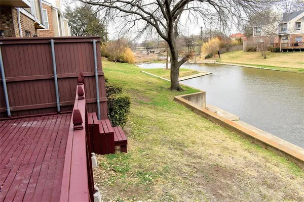 a swimming pool that has lawn chairs and a dining table under an umbrella