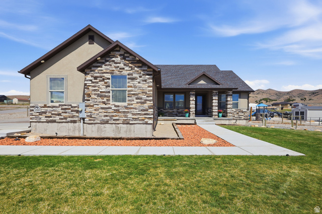 1588 West Rim Rock Drive Stockton, UT 84071 - Photo 1 of 61 Single-story residence featuring a stone and stucco exterior, dark shingle roof, and a covered front porch with stone columns