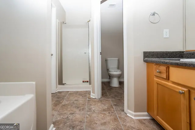 a bathroom with a granite countertop sink a toilet and shower
