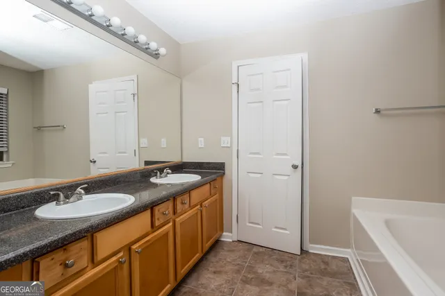 a bathroom with a granite countertop sink a mirror a vanity and a bathtub
