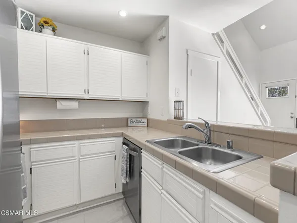 a kitchen with white cabinets sink and dishwasher