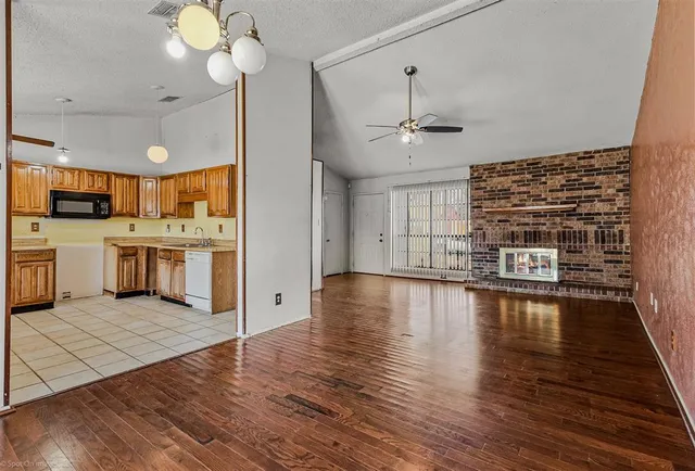 a view of a kitchen with stainless steel appliances granite countertop a stove top oven a refrigerator and a dining table with wooden floor