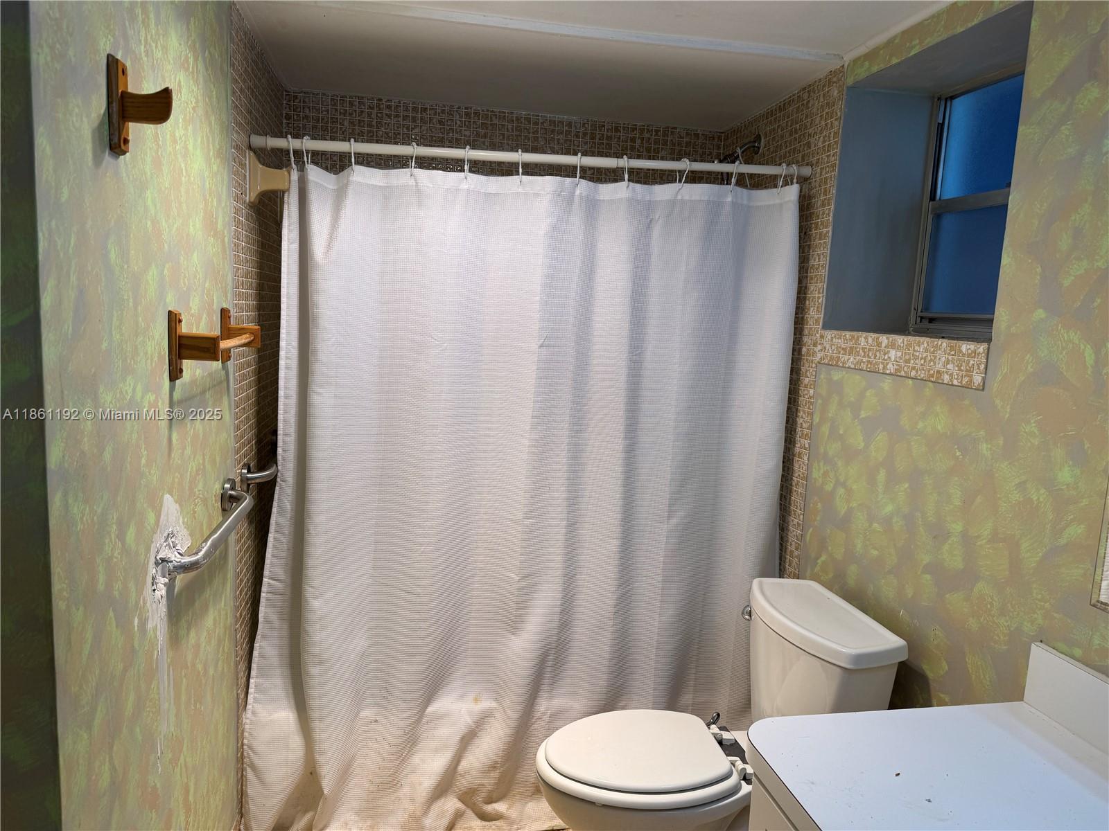 3090 Holiday Springs Boulevard, Unit 206 Margate, FL 33063 - Photo 34 of 41 a white toilet sitting next to a shower curtain