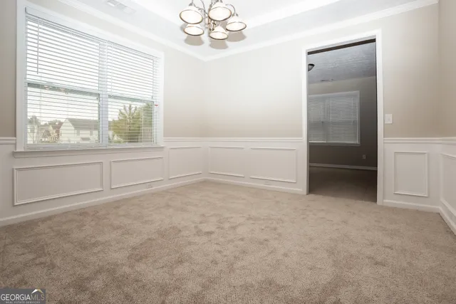 an empty room with chandelier fan and windows