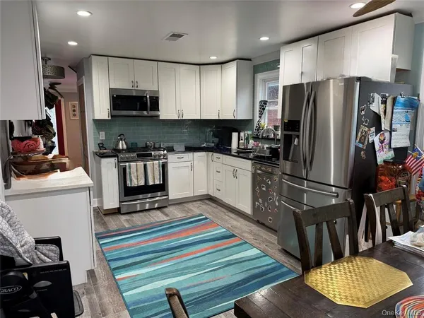 a kitchen with stainless steel appliances a refrigerator a stove a sink cabinets and a dining table