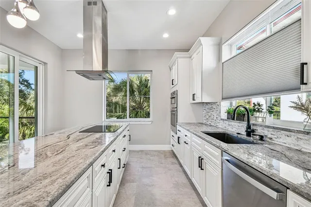 a large kitchen with granite countertop a sink and white cabinets