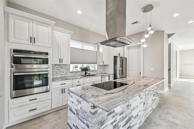 a kitchen with stainless steel appliances kitchen island granite countertop a stove and cabinets