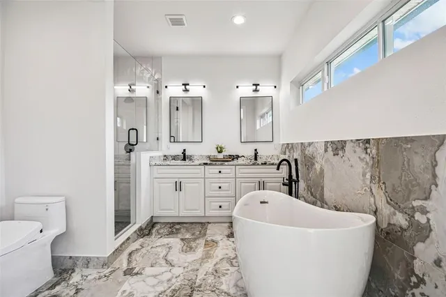 a spacious bathroom with a bathtub sink mirror and toilet