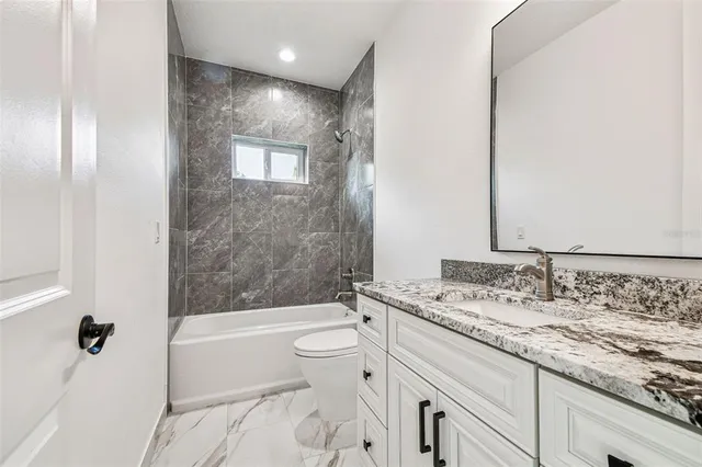 a bathroom with a granite countertop sink a toilet and bathtub