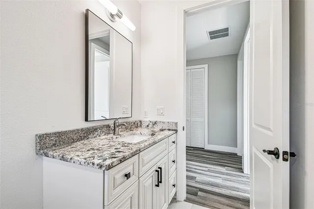 a bathroom with a granite countertop sink and a mirror