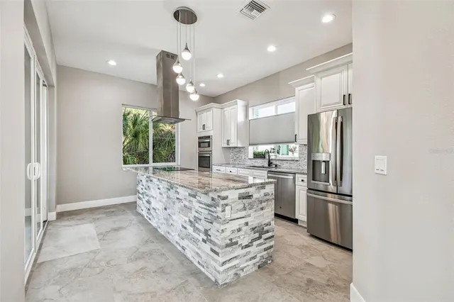 a kitchen with stainless steel appliances kitchen island granite countertop a refrigerator and a stove